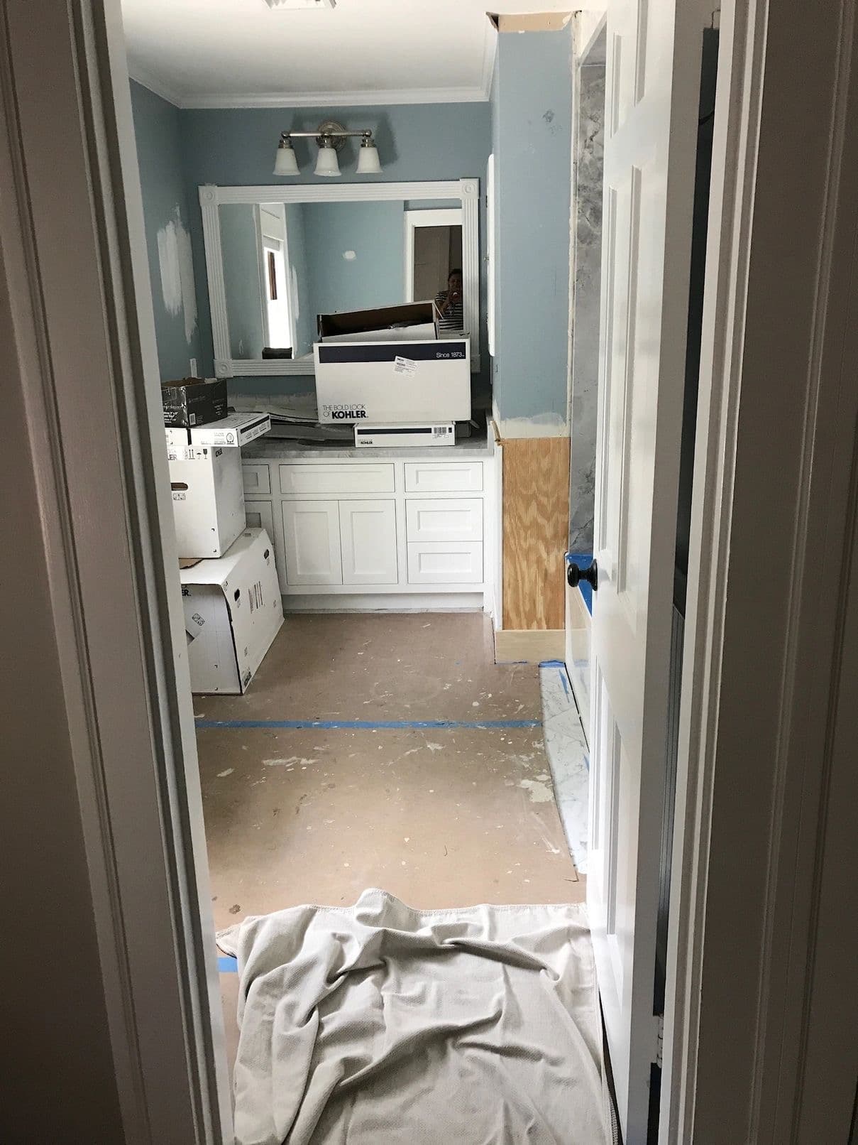 Bathroom before final construction cleaning — fixture cartons, bare subfloor and dust