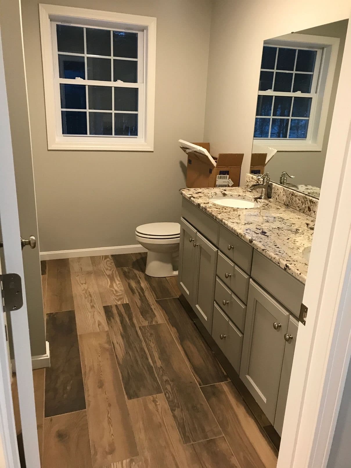 Bathroom after construction cleaning — granite vanity, mirror and tile floor