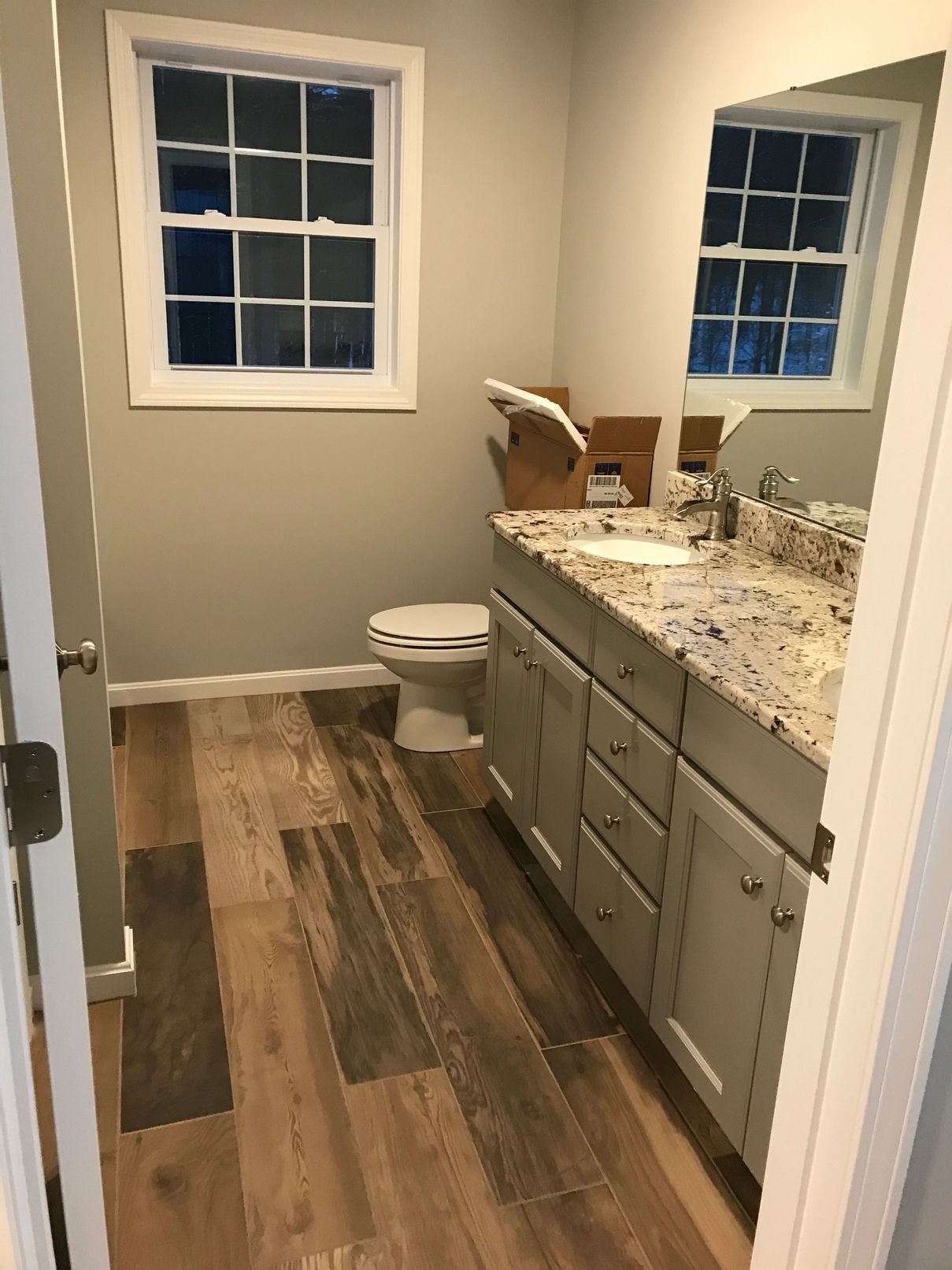 Bathroom after construction cleaning — granite vanity, mirror and tile floor
