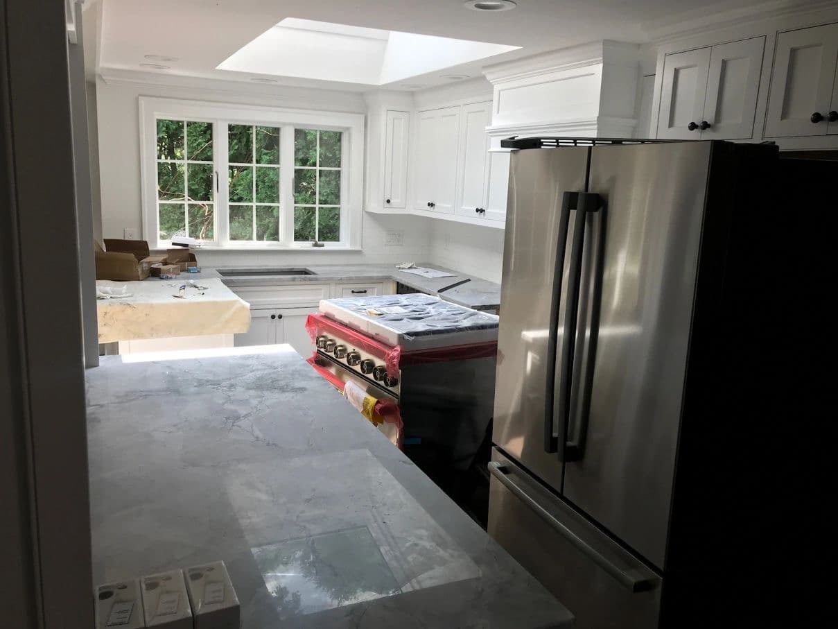 Kitchen before post-construction cleaning — construction dust, protective film and packaging throughout