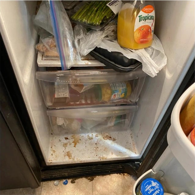 Refrigerator interior before cleaning — spills dried onto the floor of the cabinet and crumbs around the crisper drawers