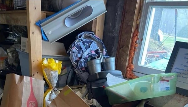Basement corner before cleaning — bags, boxes and equipment stacked against the wall and across the floor