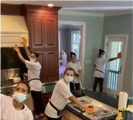 Five members of the Vcleaning team cleaning a kitchen — cabinets, range, counters and a glazed door
